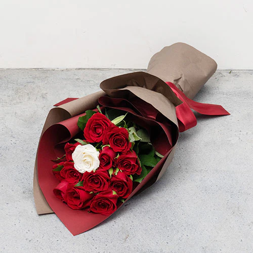 プロポーズ用の赤い薔薇の花束で中に１輪だけ花びらメッセージの入った白い薔薇もある