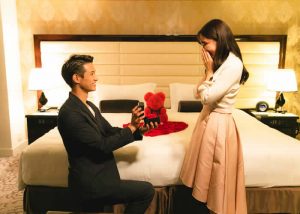 ホテルの部屋でプロポーズする男性と喜ぶ女性