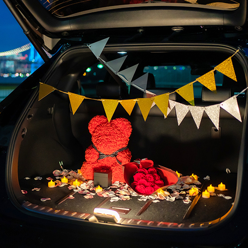 車のトランクルームをプロポーズ用に赤いバラの花束やローズベア、ガーランドで飾りつけた様子