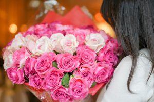 ピンクと白の薔薇大きな花束を抱えた女性
