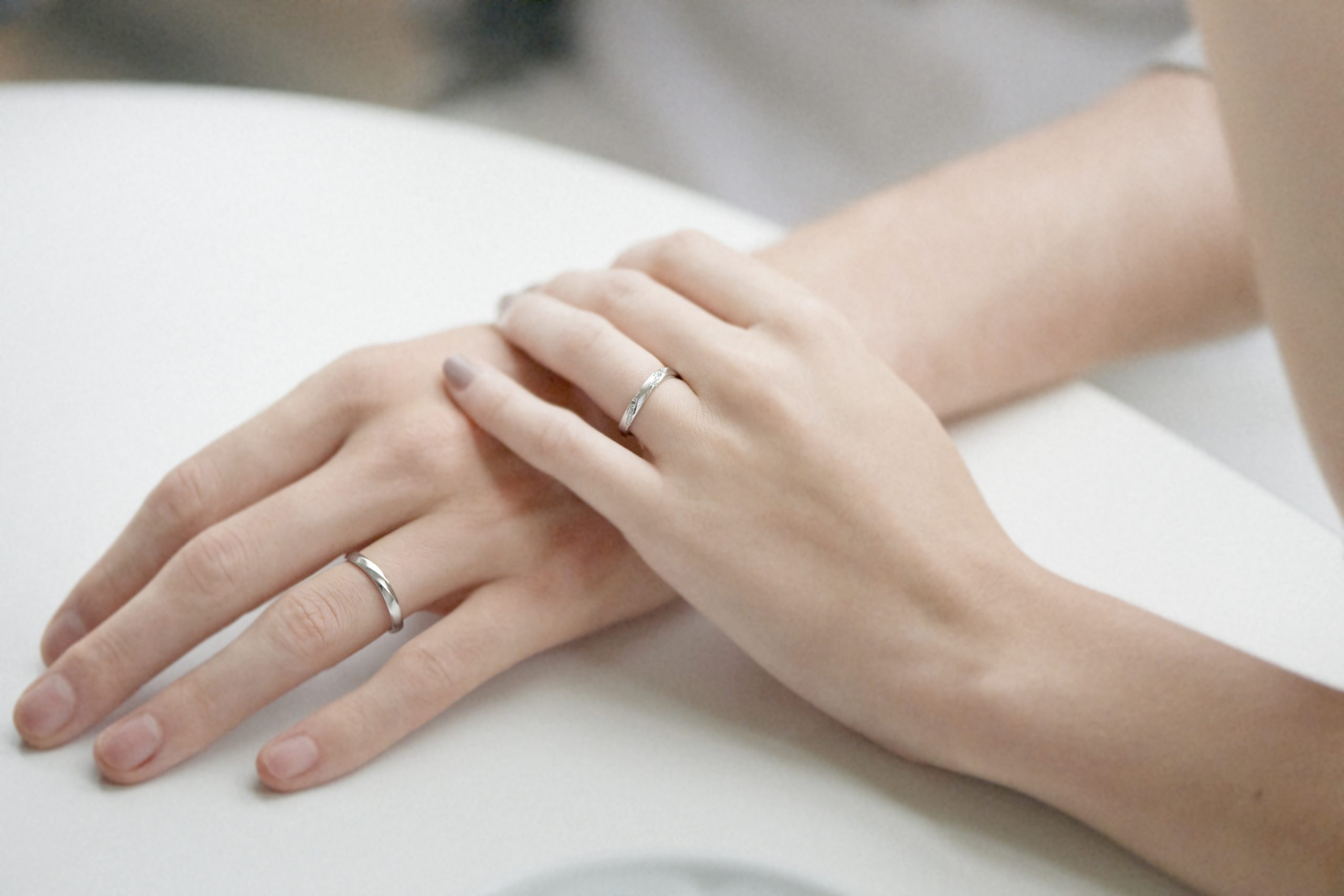 結婚指輪を身につけ左手同士を重ねている夫婦の手元
