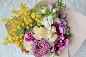 紫のバラとカーネーション、ミモザと白いストックを束ねたナチュラルなプロポーズブーケ